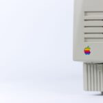 Close-up of a vintage computer monitor featuring a colorful logo on a minimalist background.