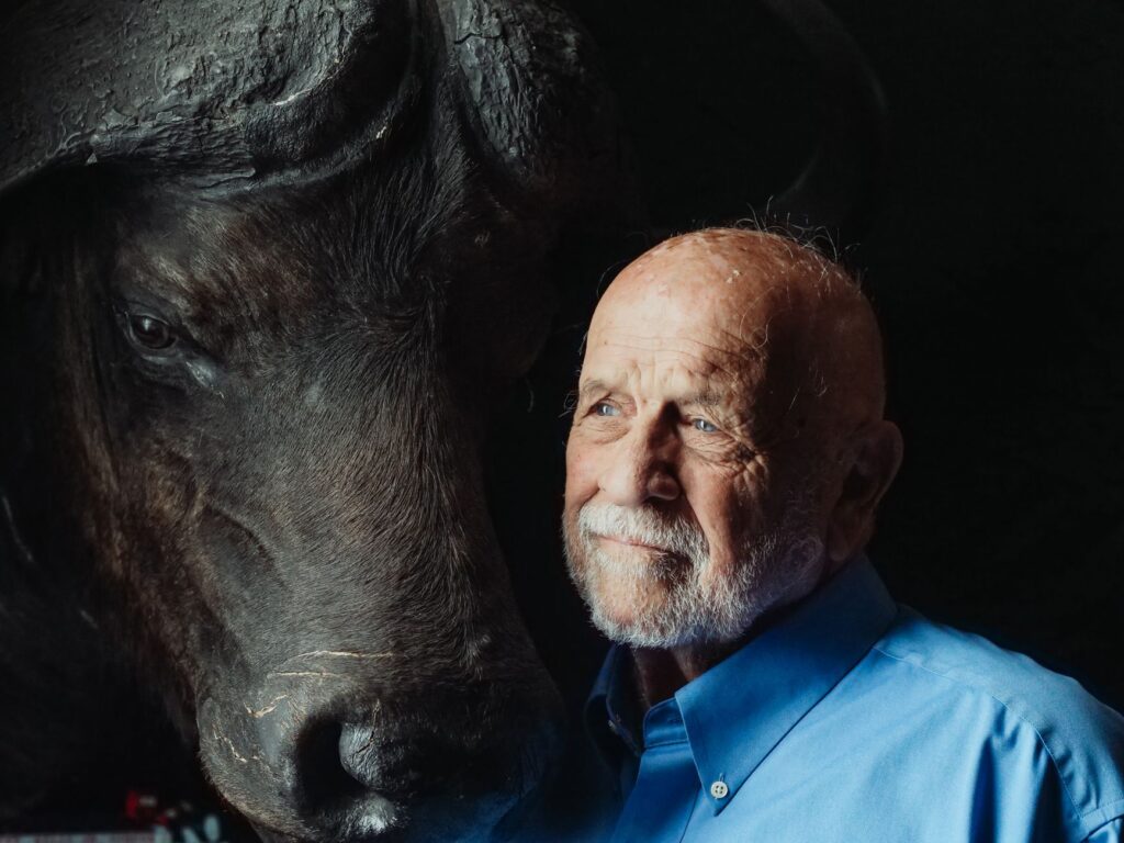 Portrait of an elderly man contemplating beside a buffalo, evoking a sense of connection and reflection.