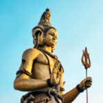 A stunning statue of Shiva with blue sky backdrop, showcasing intricate detail and cultural significance.