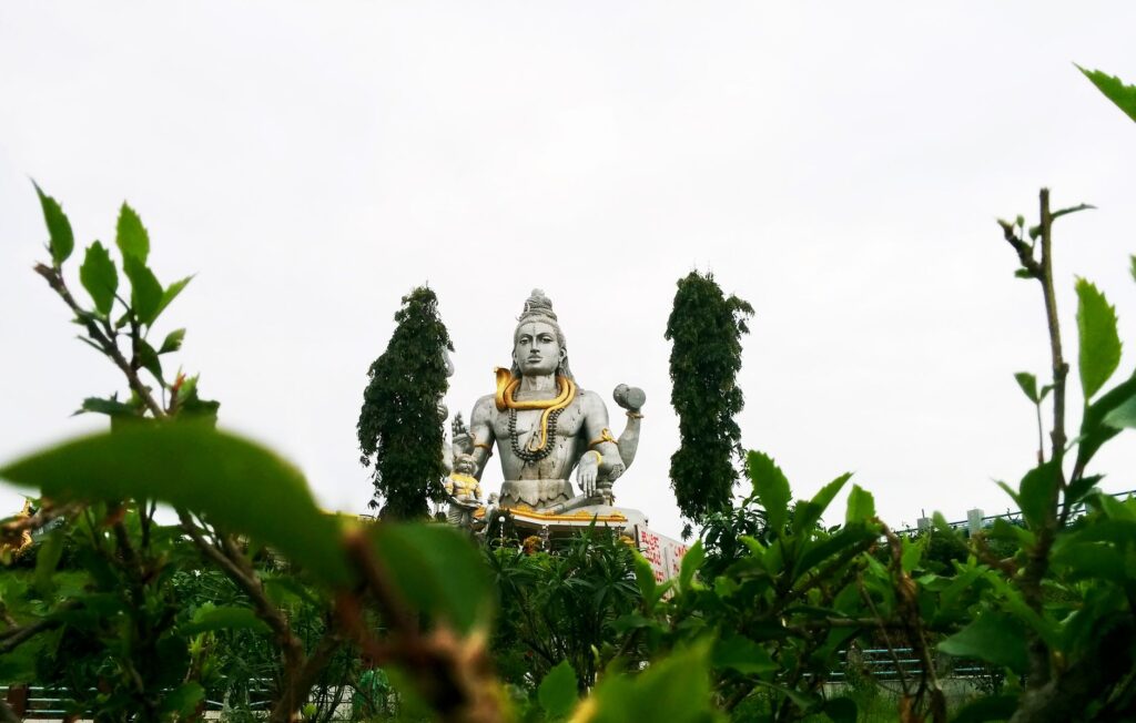 A stunning view of a Shiva statue amidst lush greenery in an outdoor setting.
