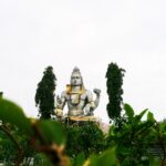A stunning view of a Shiva statue amidst lush greenery in an outdoor setting.
