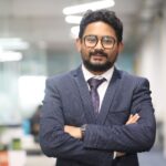 Confident man in a suit standing in a modern office, showcasing professionalism.