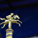 Close-up of a golden horse racing trophy with a rich blue background, symbolizing victory.