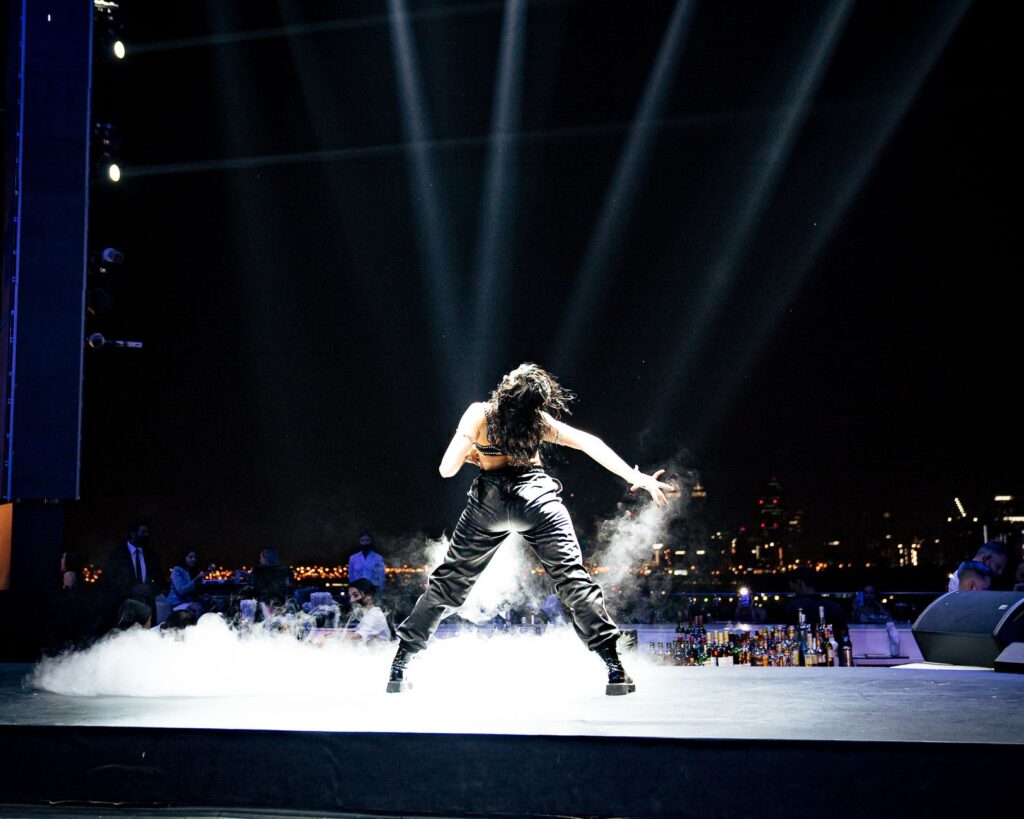A powerful back view of a performer on stage with dramatic city skyline at night.