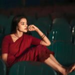 Elegant woman in a red dress seated in a theater, exuding grace and contemplation.