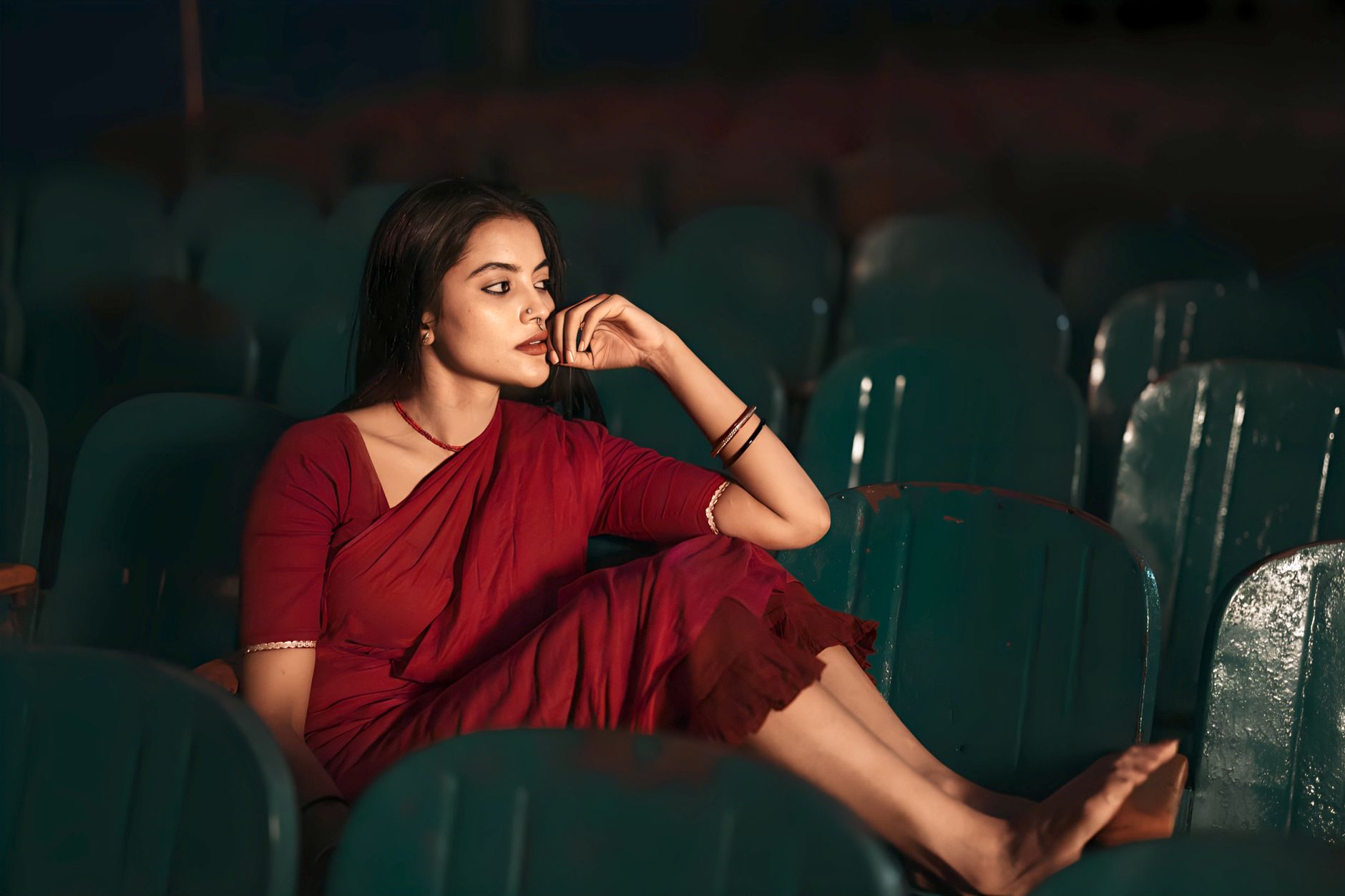 Elegant woman in a red dress seated in a theater, exuding grace and contemplation.