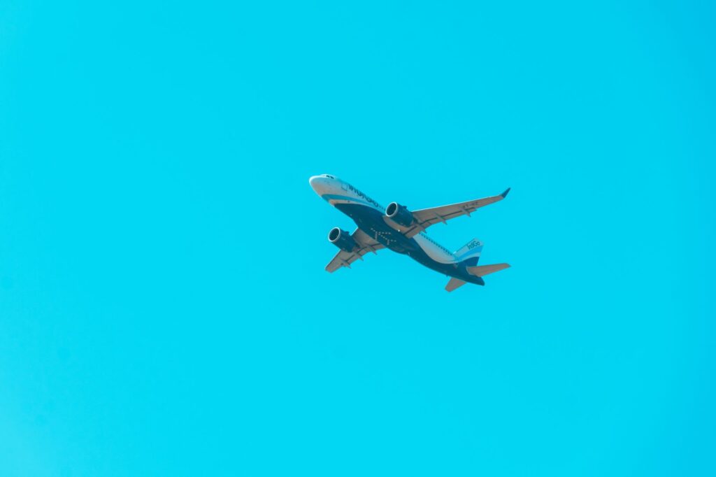 A commercial jet soars through a bright blue sky, showcasing aviation power.