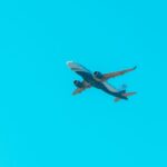 A commercial jet soars through a bright blue sky, showcasing aviation power.