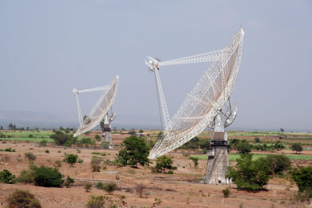 Two large satellite dishes in a rural field near Pune, India, capturing signals.