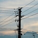 Silhouette of power lines and pole against a vibrant sunset sky.