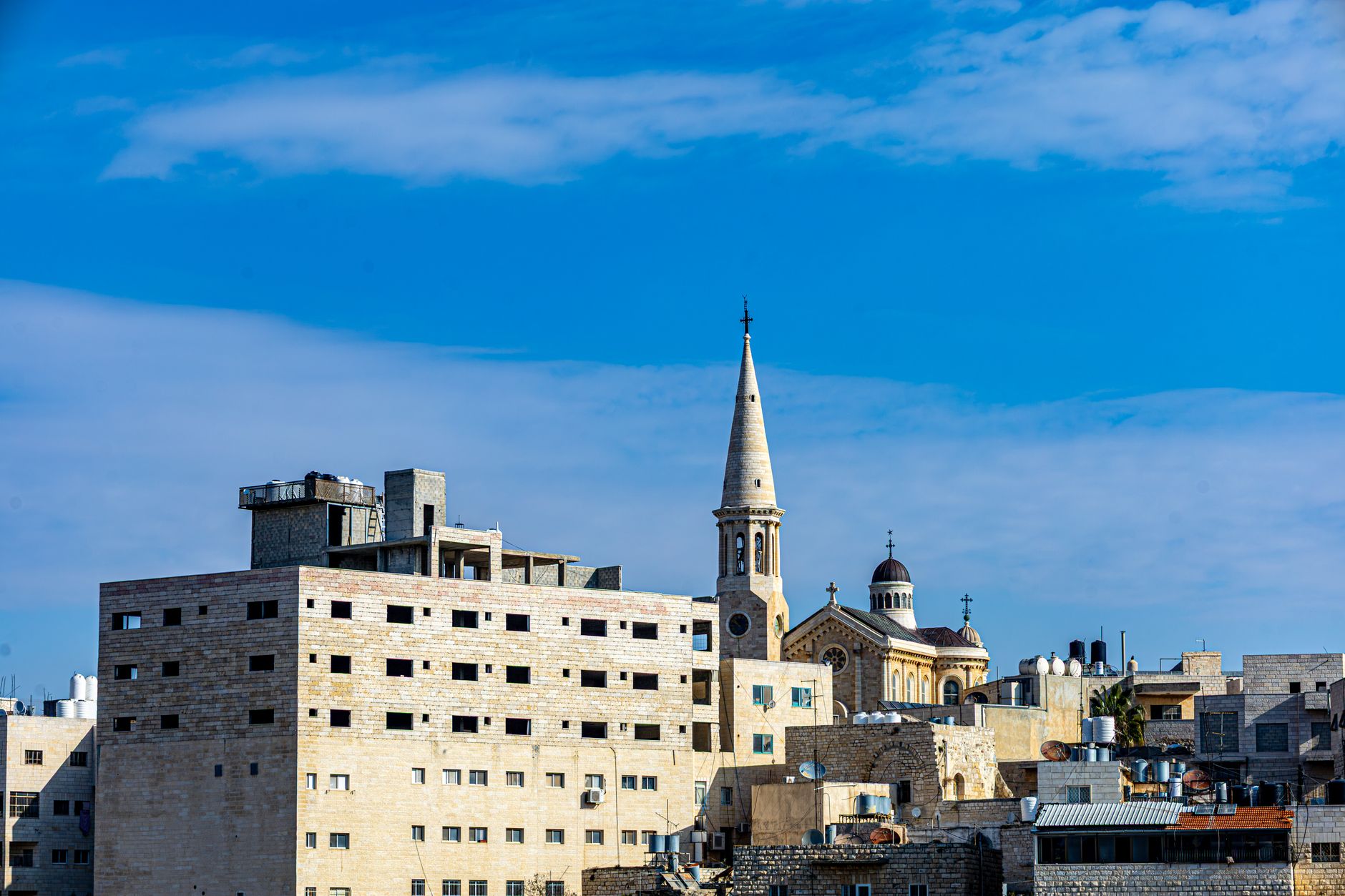 Scenic view of Bethlehem buildings with a prominent church spire under a bright blue sky.