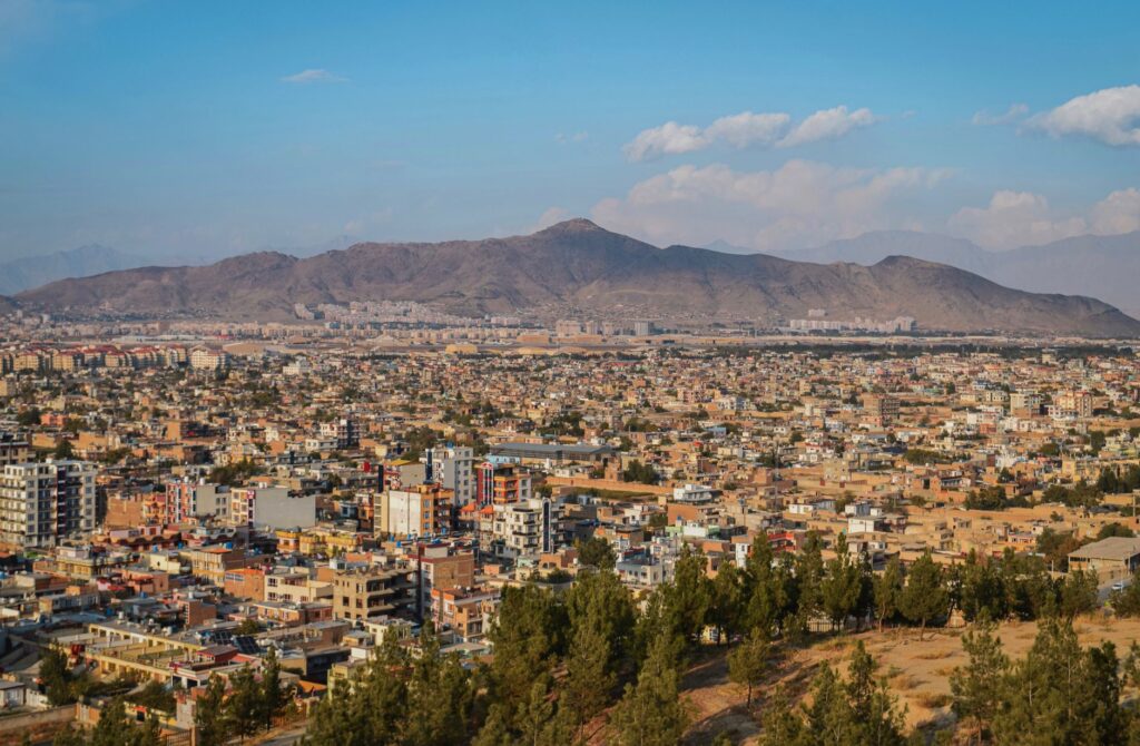 Aerial cityscape of Kabul, Afghanistan with mountains in the background.