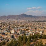 Aerial cityscape of Kabul, Afghanistan with mountains in the background.