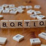 Scrabble tiles spelling 'abortion', highlighting the debate on reproductive rights.