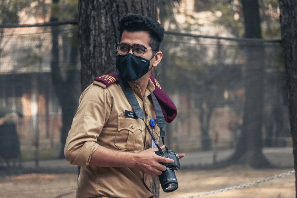 Portrait of a masked photographer amid the outdoors in Dhaka, showcasing urban exploration.