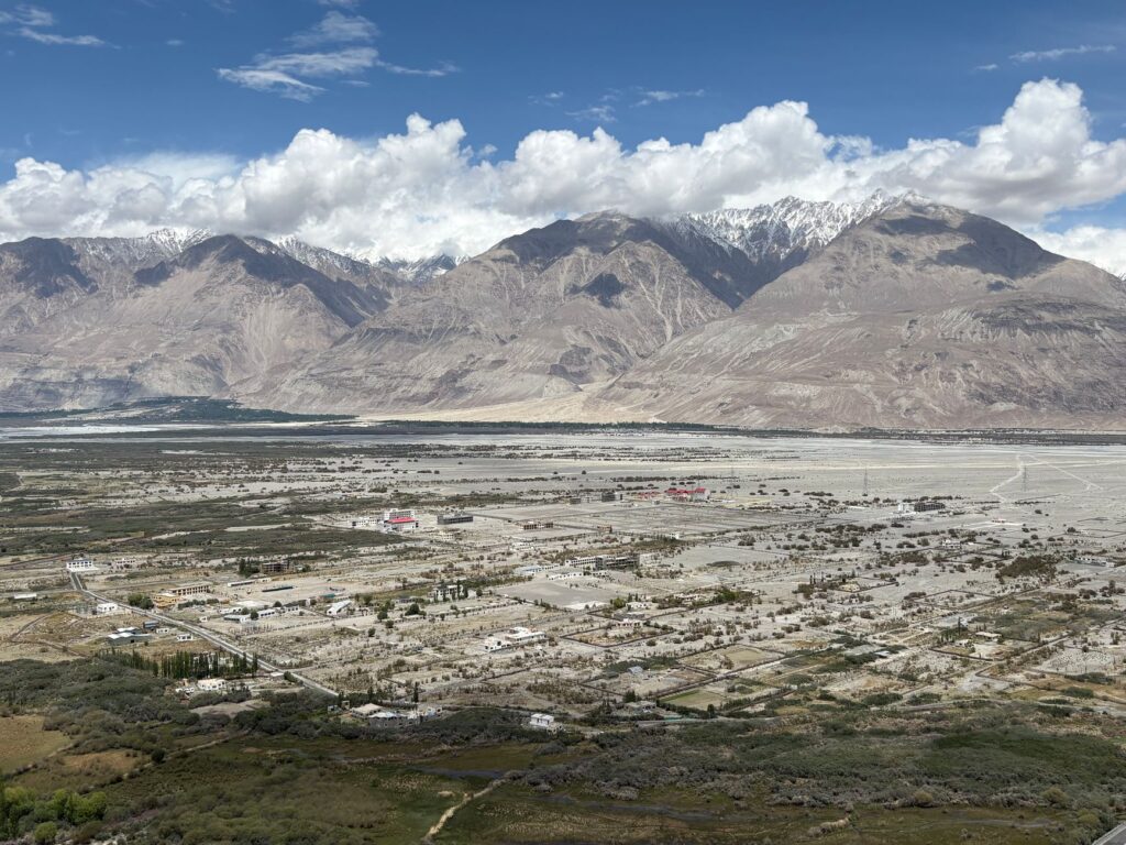 A stunning aerial view of Nubra Valley with mountains and scattered settlements beneath a blue sky.