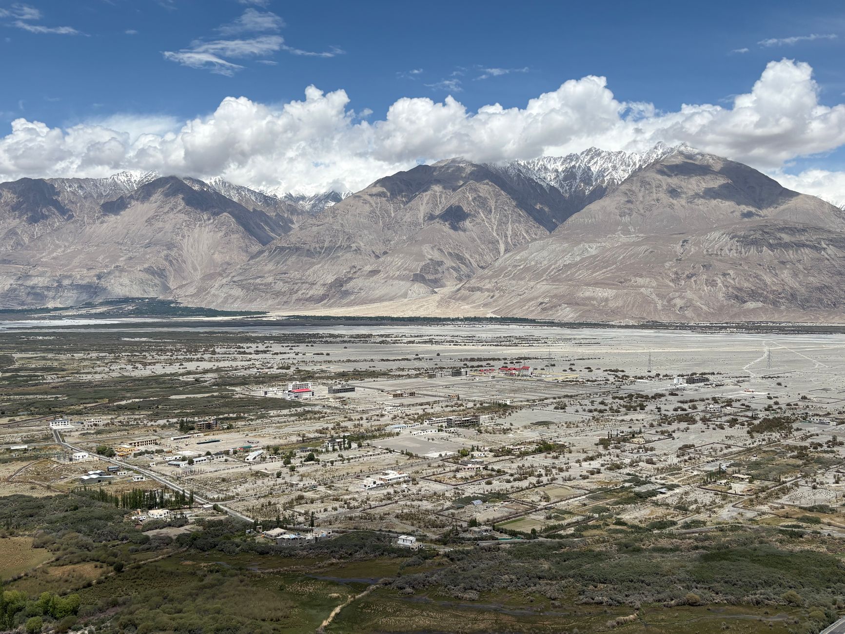A stunning aerial view of Nubra Valley with mountains and scattered settlements beneath a blue sky.