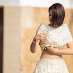 Captivating portrait of a stylish woman in a sophisticated white outfit in a sunlit setting.