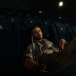 Man in uniform resting on cinema seats during a quiet moment at work.