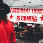 Banner promoting a political event for Donald Trump in Wheeling, WV with market stalls.