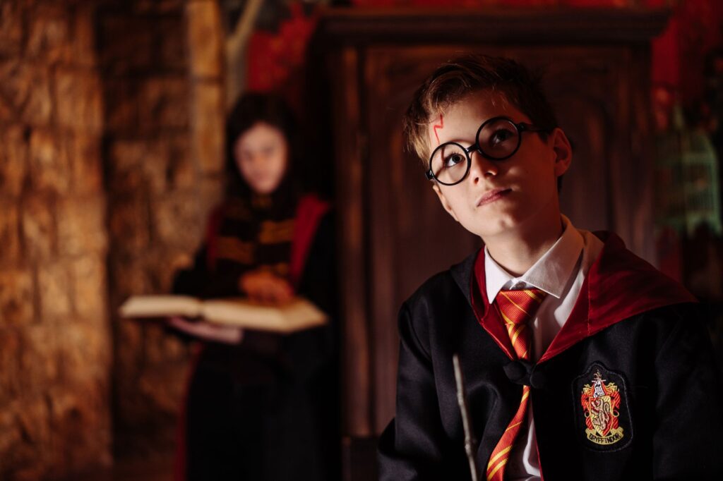 Young boy dressed as a wizard with a wand, engaging in fantasy role-play indoors.