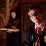 Young boy dressed as a wizard with a wand, engaging in fantasy role-play indoors.