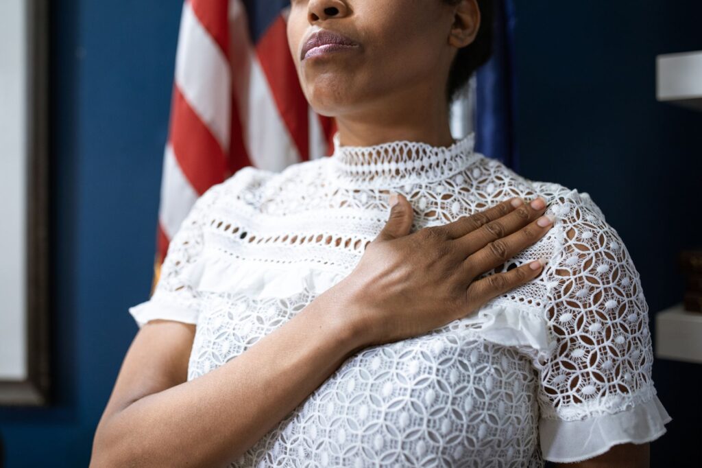 A confident woman in white lace dress pledges allegiance, symbolizing leadership and patriotism.
