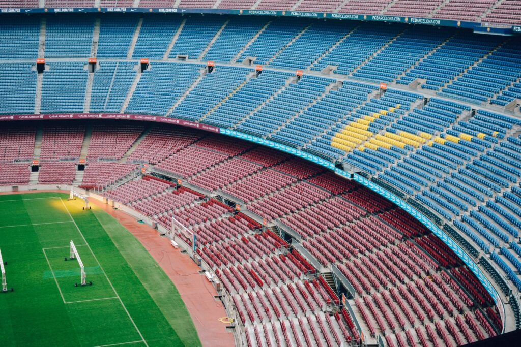 Aerial view of the empty Camp Nou stadium in Barcelona with colorful seats and green field.
