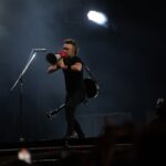 Musician with megaphone on stage during night concert, energizing the crowd.