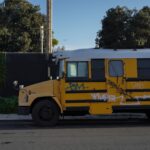 A vintage yellow school bus with graffiti parked on a street in Los Angeles, CA.