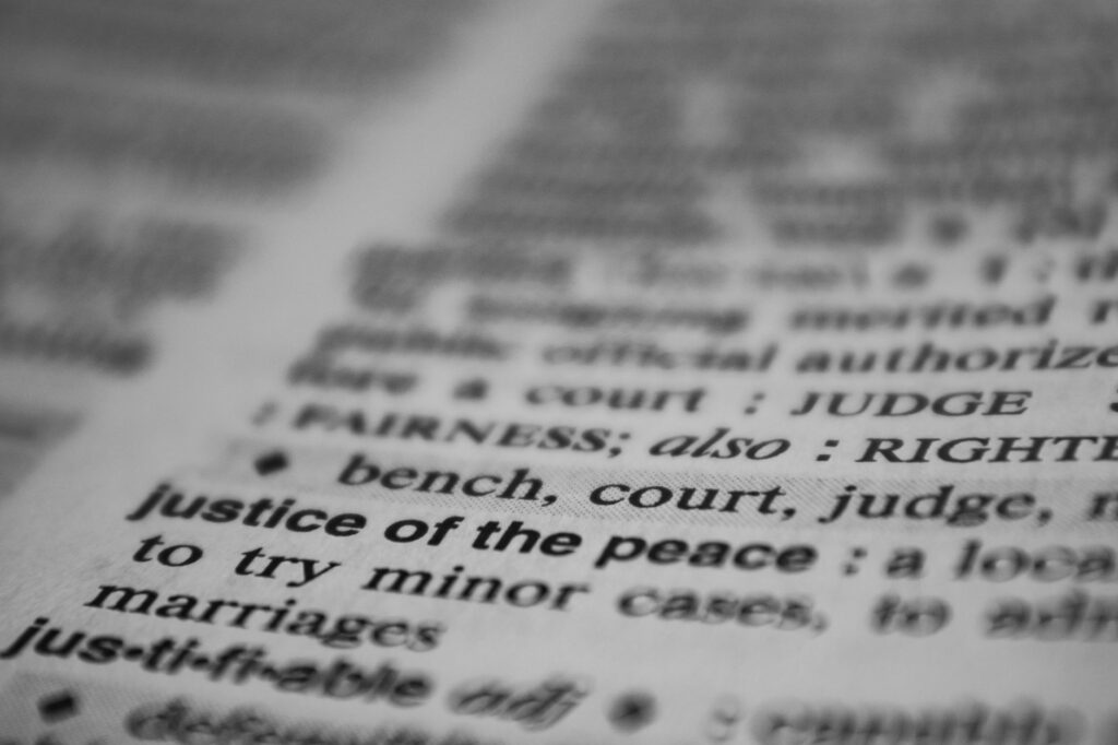 Selective focus on the word 'justice' in a dictionary, conveying law and fairness concepts.