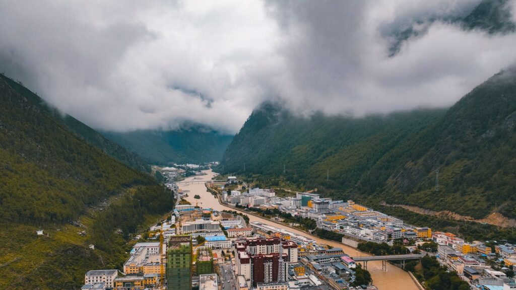 Aerial shot of Nyingchi, Tibet, showcasing a town nestled between lush mountains and a winding river.