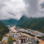 Aerial shot of Nyingchi, Tibet, showcasing a town nestled between lush mountains and a winding river.