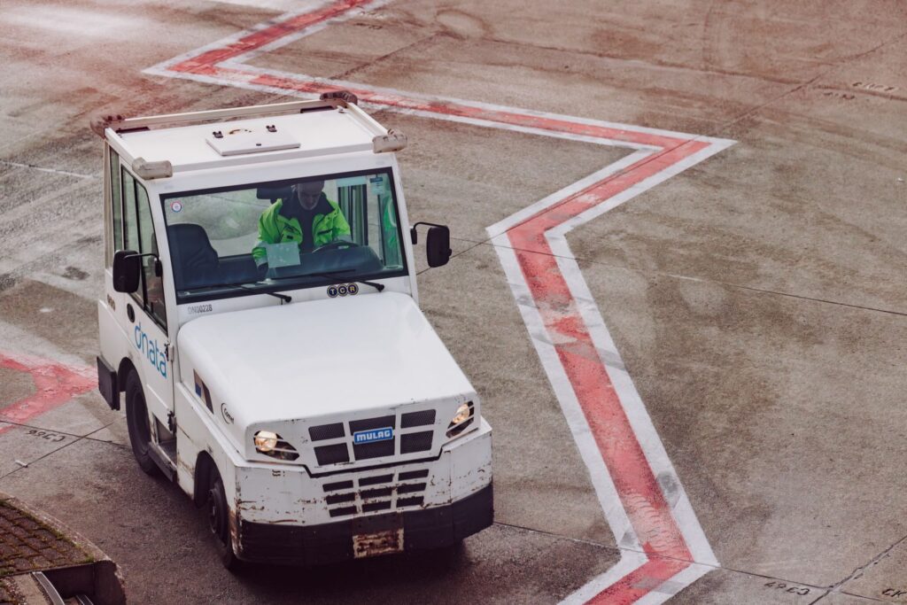 A ground crew vehicle navigates the airport tarmac during daytime operations.