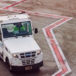 A ground crew vehicle navigates the airport tarmac during daytime operations.