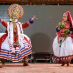 Vibrant Kathakali dancers performing in traditional costumes at a cultural event in Kerala, India.
