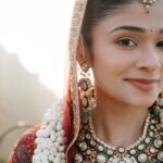 Beautiful Indian bride adorned with traditional jewelry and floral garland, smiling softly against a soft blurred background.
