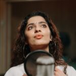 Portrait of a woman singing in a professional recording studio.