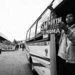 A street protest with demonstrators and a bus in urban surroundings.