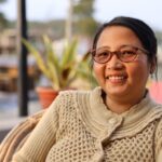 Happy woman with eyeglasses and sweater enjoying the outdoors in Manipur, India.