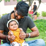 A loving father and his baby daughter enjoy a sunny day together outdoors.