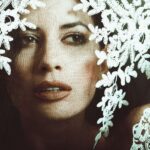 Artistic portrait of a stylish woman peering through a delicate lace veil.
