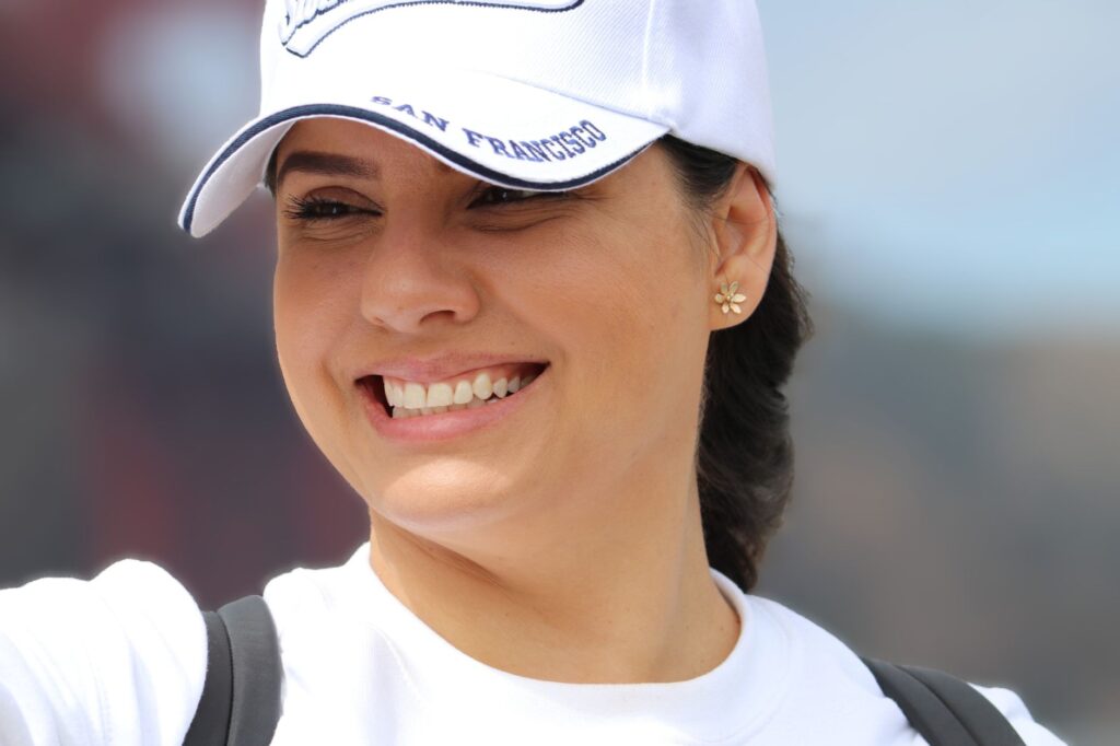 Smiling woman wearing San Francisco cap enjoying a sunny day outdoors.