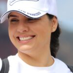 Smiling woman wearing San Francisco cap enjoying a sunny day outdoors.