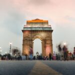 A stunning view of India Gate in New Delhi at sunset with a dynamic crowd.