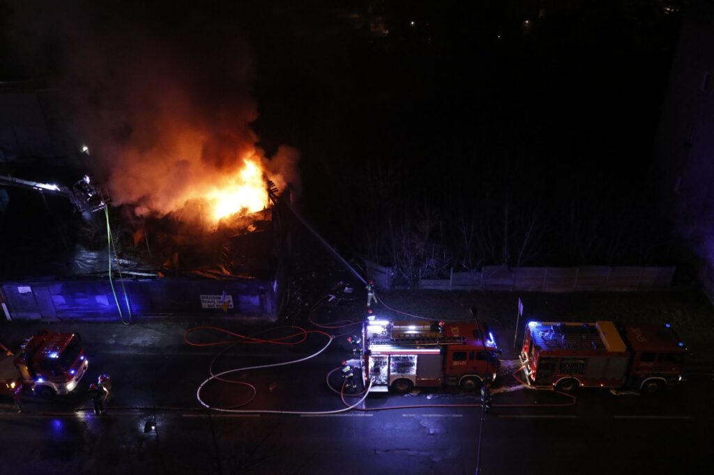 A dramatic nighttime scene of firefighters extinguishing a building fire.