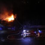 A dramatic nighttime scene of firefighters extinguishing a building fire.