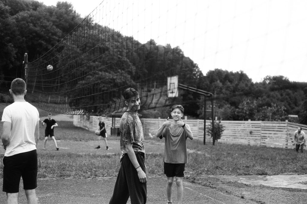 Boys playing volleyball outdoors in Lviv, Ukraine. Black and white capture shows physical activity.