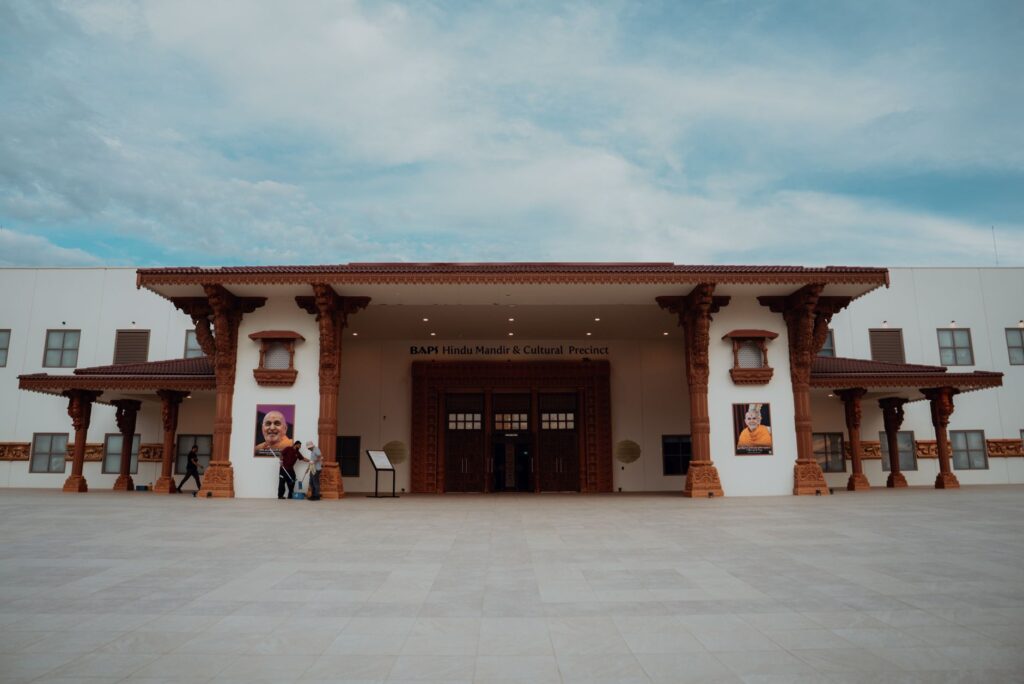 Stunning exterior view of BAPS Hindu Mandir and Cultural Precinct with detailed architecture under a clear blue sky.