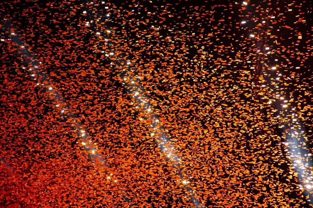 A dazzling display of orange confetti illuminated against a dark night sky, perfect for festive celebrations.